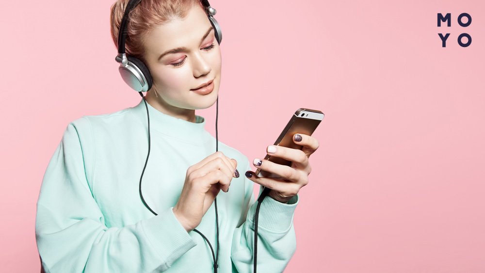 Девушка слушает музыку на телефоне в наушниках