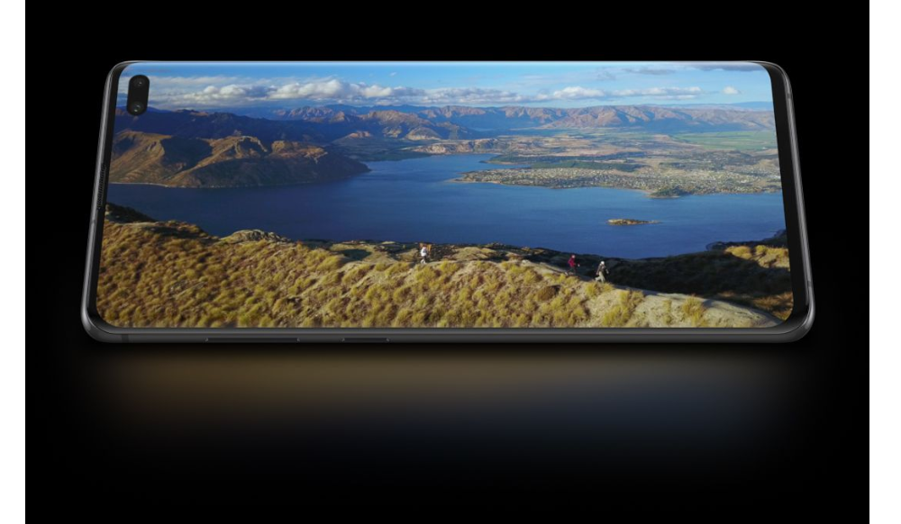 Galaxy S10 plus in landscape mode seen from the front with a photo of people hiking along seaside cliffs shown onscreen. While scrolling, the phone starts to tilt back.